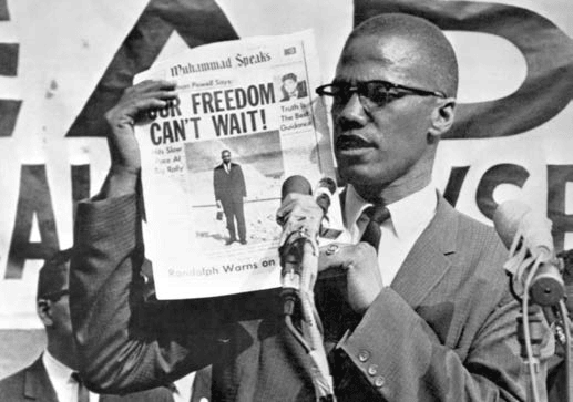 Malcolmx holding newspaper with 'Our Freedom Can't Wait' headline