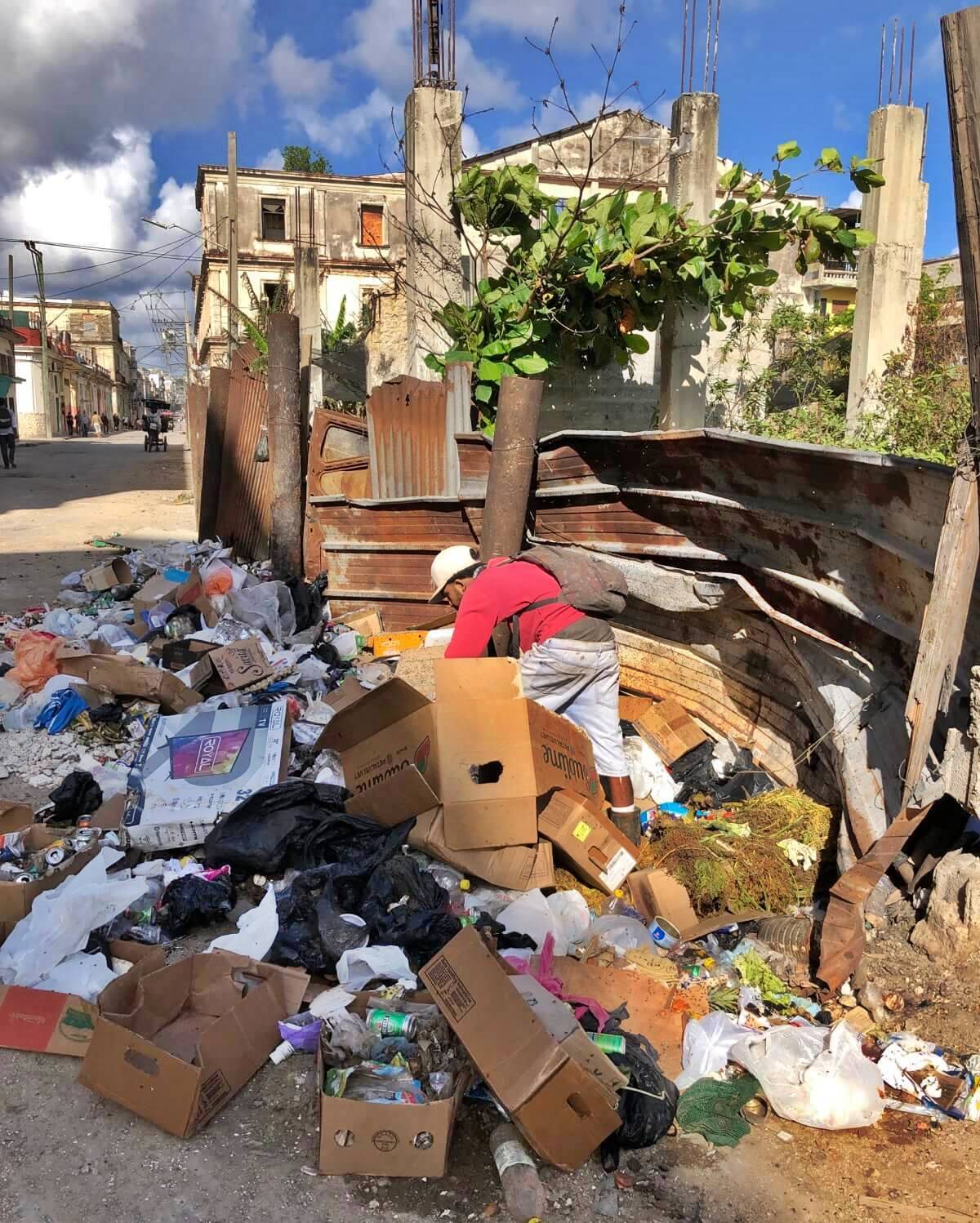 Poor person rummages through trash pile in Havana